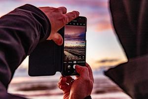 homme prise une image pendant une coloré le coucher du soleil plus de le polonais baltique mer pendant le vacances photo