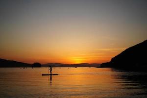 beau coucher de soleil avec des silhouettes de personnes sur sup-surfeur. photo