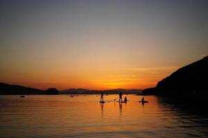 beau coucher de soleil avec des silhouettes de personnes sur sup-surfeur. photo