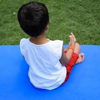 asiatique intelligent enfant Faire yoga pose dans le société parc Extérieur, enfants yoga pose. le peu garçon Faire yoga et méditation exercer. photo