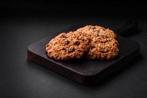 délicieux cuit flocons d'avoine raisin biscuits sur une foncé béton Contexte photo