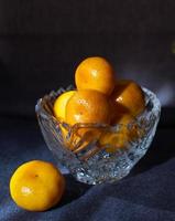 Mandarines jaunes dans un vase en cristal sur fond sombre