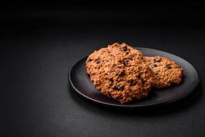 délicieux cuit flocons d'avoine raisin biscuits sur une foncé béton Contexte photo