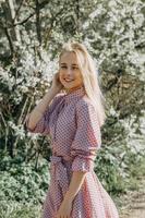 blond fille sur une printemps marcher dans le jardin avec Cerise fleurs. femelle portrait, fermer. une fille dans une rose polka point robe. photo