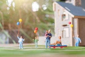personnes miniatures, famille heureuse jouant dans la pelouse de la cour. concept de vie à la maison photo