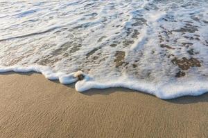 vagues avec blanc mousse à le bien le sable de le plage pendant lever du soleil dans Egypte macro photo