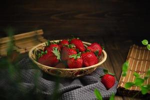 osier panier avec sucré rouge des fraises sur une foncé en bois tableau. photo