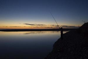 paysage marin avec une silhouette de pêcheur photo