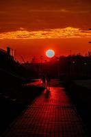 rouge le coucher du soleil dans le ville avec une route et en marchant couple de gens dans l'amour photo
