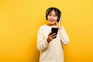 asiatique femme Heureusement en utilisant le téléphone et écoute à la musique relaxant avec musique. sur une confortable journée. Danse et relaxation concept. écoute à la musique en ligne photo