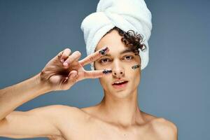 Beau gars avec une serviette sur le sien tête nu épaules produits de beauté nettoyer peau photo