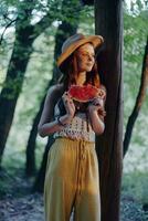 femme en mangeant pastèque sur une été journée dans le campagne et en train de regarder le le coucher du soleil photo