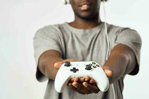 une homme de africain apparence dans écouteurs avec une manette de jeu dans le sien mains pièces vidéo Jeux La technologie photo