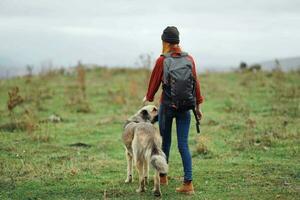 femme avec sac à dos sur sa retour la nature tourisme en marchant chien photo