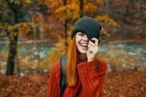 femme dans une chapeau et une chandail avec une sac à dos sur sa retour amusement l'automne paysage rivière photo