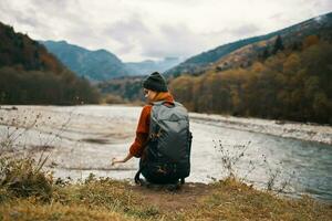 femme promeneur sur le banques de le rivière dans l'automne et montagnes dans le distance des nuages temps la nature photo