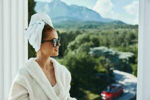 jolie femme dans des lunettes de soleil à le Hôtel sur le balcon Montagne vue photo