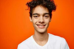 gars avec frisé cheveux dans une blanc T-shirt émotions proche en haut photo