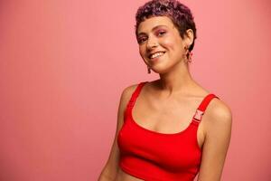 mode portrait de une femme avec une court la Coupe de cheveux de violet Couleur et une sourire avec les dents dans une rouge Haut sur une rose Contexte bonheur photo