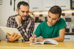 père est portion le sien fils avec apprentissage. elles ou ils sont Faire devoirs ensemble. photo