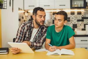 père est portion le sien fils avec apprentissage. elles ou ils sont Faire devoirs ensemble. photo