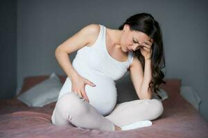 Enceinte femme avec mal de crâne à maison. photo