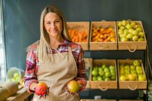 femme travaux dans des fruits et des légumes magasin. elle est en portant mangues. photo