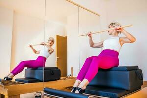 blond femme est exercice sur pilates réformateur lit dans sa maison. photo