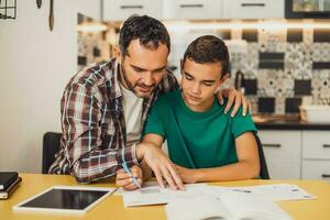 père est portion le sien fils avec apprentissage. elles ou ils sont Faire devoirs ensemble. photo