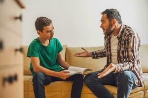 père est portion le sien fils avec apprentissage. elles ou ils sont Faire devoirs ensemble. photo