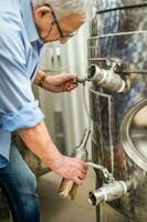 Sénior homme en fonctionnement une du vin réservoir dans le vignoble photo