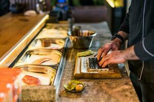 Sushi chef en train de préparer nourriture à une Sushi bar. photo