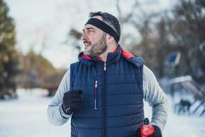 adulte homme est fonctionnement dans parc dans l'hiver. photo