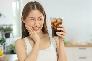 santé asiatique Jeune femme émouvant joue, expression, Souffrance de mal aux dents, pourriture ou sensibilité cavité molaire dent, les dents ou inflammation boisson froid, pétillant l'eau à sensible à la maison les dents gens photo