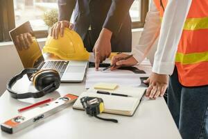 constructeur deux jeunes ingénieurs asiatiques et une femme architecte discutent de la construction d'un plan pour suivre le projet de construction d'une usine industrielle sur le site. notion de travailleur. photo