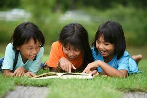groupe de les enfants mensonge en train de lire sur herbe champ photo