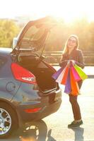 caucasien femme en mettant sa achats Sacs dans le voiture tronc photo