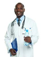 portrait de une souriant Masculin médecin en portant bouteille de l'eau sur blanc photo