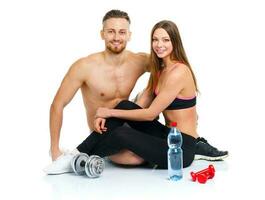 sport couple - homme et femme après aptitude exercice avec haltères et bouteille de l'eau séance sur le blanc photo