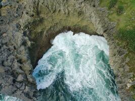 aérien vue de le vagues frappe le côtier récifs photo