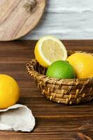citrons et citrons verts dans panier sur en bois tableau. photo