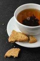 tasse de noir thé avec avoine biscuits sur foncé Contexte. photo