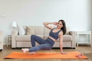 asiatique femme exercice à maison, élongation. temps pour yoga. attrayant et en bonne santé Jeune femme Faire des exercices tandis que repos à maison. Jeune femme exercice à maison, intérieur photo