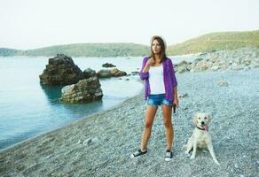 femme avec une chien sur une marcher sur le plage photo