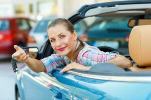 Jeune jolie femme séance dans une convertible voiture avec le clés dans main photo