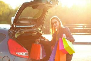 caucasien femme en mettant sa achats Sacs dans le voiture tronc photo