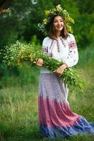 Jeune souriant fille dans ukrainien costume avec une couronne sur le sien tête dans une Prairie photo
