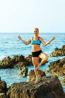 athlétique femme relaxant - pratiquant yoga sur le rochers par le mer photo