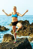 athlétique femme relaxant - pratiquant yoga sur le rochers par le mer photo