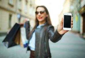 en ligne achats concept - magnifique femme avec achats Sacs et intelligent téléphone dans le mains photo